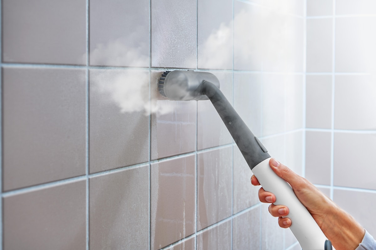 Handheld electric steam scrubber cleaning bathroom tiles during move-in move-out cleaning
